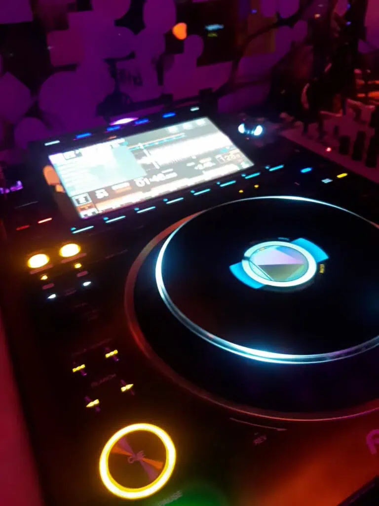 Contrôleur DJ professionnel lors d'un événement en Colombie, illuminé de lumières colorées, prêt à mixer de la musique et à animer la fête dans une ambiance vibrante organisée par Eventario.