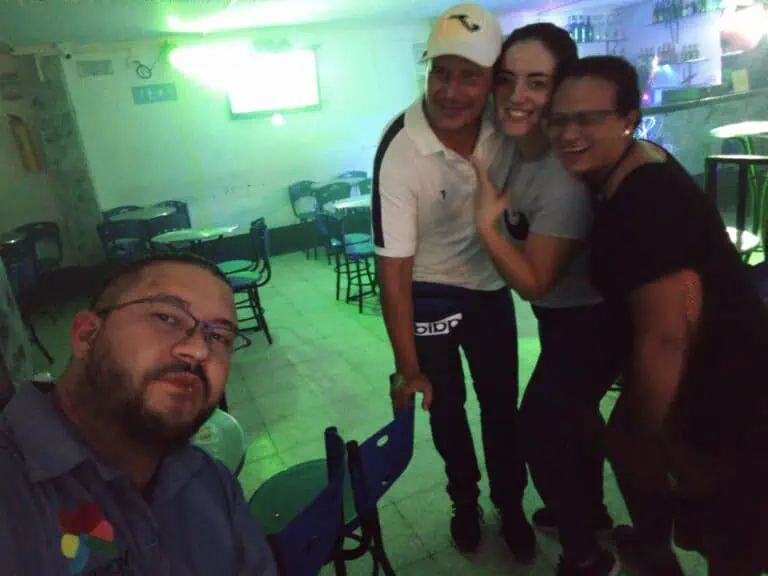 Disfrutando de una reuni&oacute;n social en un bar con ambiente festivo y luces de ne&oacute;n color verde, personas felices y convivientes, ideal para eventos y networking en Colombia.