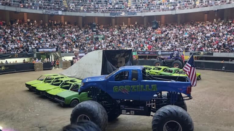 Coches de competencia y monstro de carreras en el Coliseo para eventos de autos, con una multitud de espectadores en las gradas, en un espectáculo de velocidad y adrenalina en Colombia.