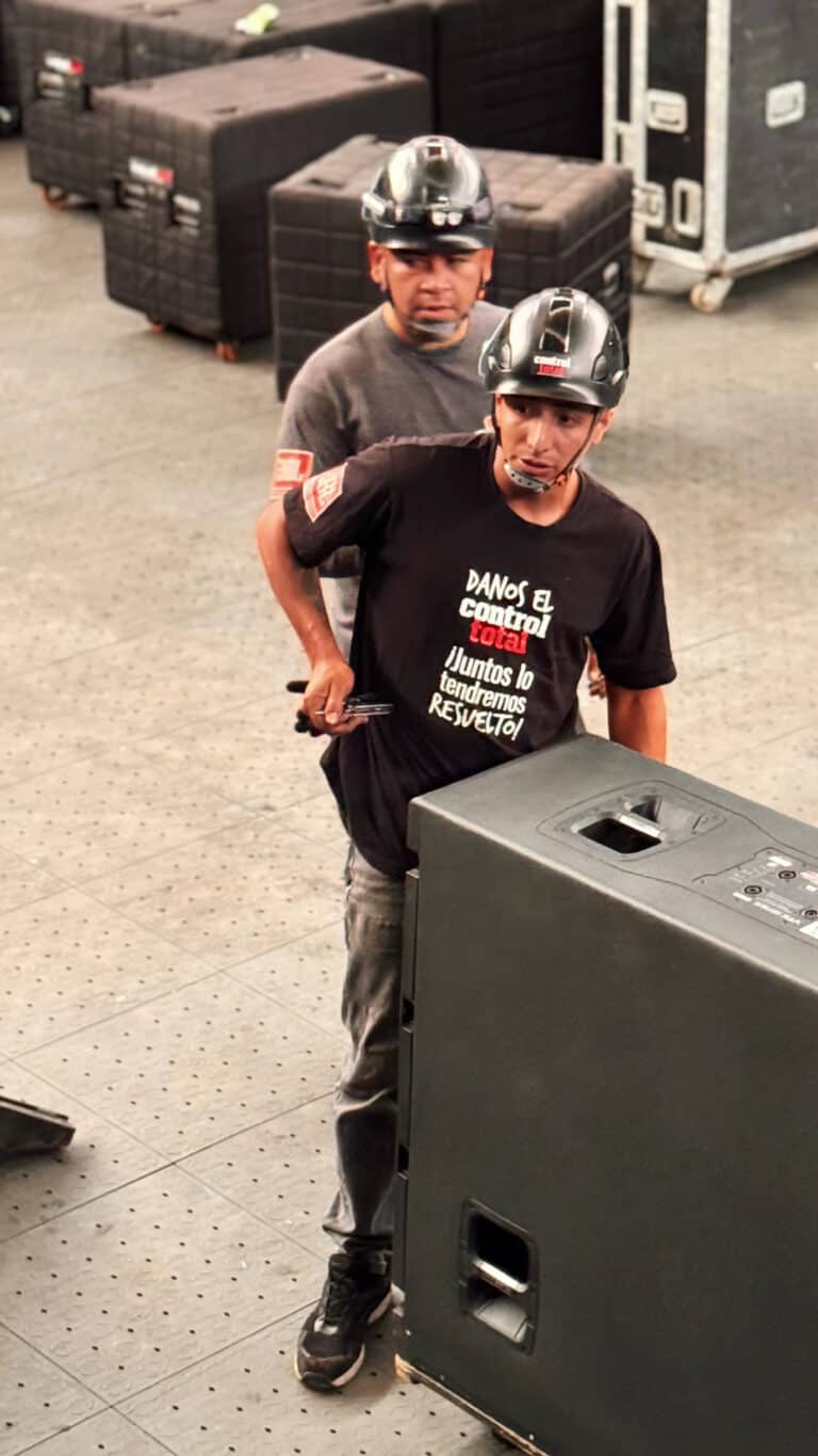 Increíbles trabajadores de eventos ajustando el equipo de sonido en un espacio de evento. La imagen refleja organización y profesionalismo en logística de eventos.