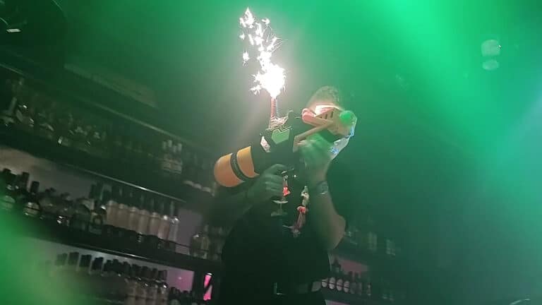 Barmans en un evento con efecto de cohete de petardo en la mano, creando un ambiente festivo y divertido en un bar o fiesta, promoviendo la organización de eventos con nuestro servicio.
