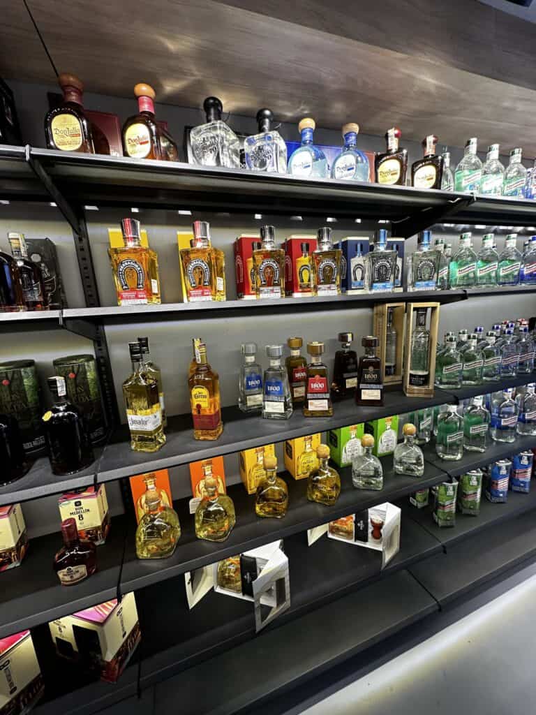 Botellas de licor en estantería de supermercado, diversas marcas y sabores de bebidas alcohólicas, exhibidas para la venta en un establecimiento comercial.