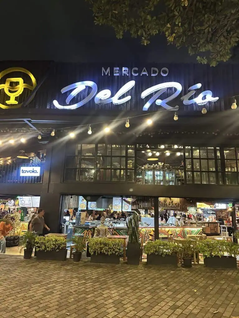 “Mercado del Río”食品店在夜晚灯火通明，气氛活跃，装饰现代，顾客们在将美食、文化和娱乐融入都市环境的空间里尽情享受。