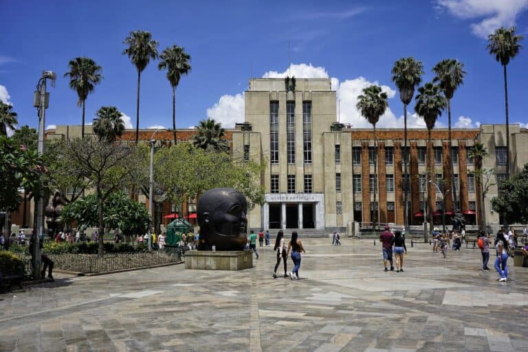 Antigua Universidad en Bogotá con palmeras, arte urbano y plaza pública, perfecta para eventos culturales y turísticos en el corazón de la ciudad.