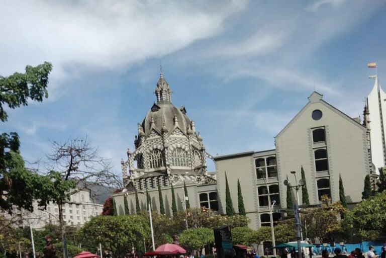 Catedral de Cuenca, iglesia histórica en el centro de la ciudad, con arquitectura gótica y la histórica plaza principal, rodeada de árboles y actividad urbana.
