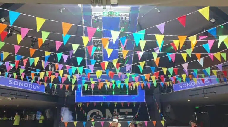 五彩缤纷的三角旗装饰着封闭场地内的活动或派对，场地内设有舞台和DJ。这是哥伦比亚举办社交活动或音乐会的热闹非凡的场所。