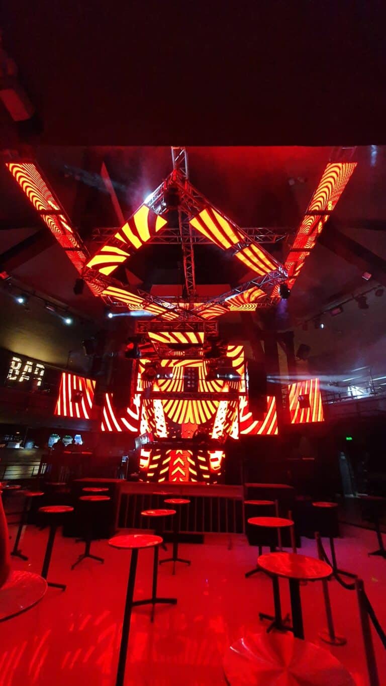 Luces y pantallas LED en escenario de evento en interior, iluminación de fiesta con efectos visuales vibrantes, ambiente de concierto o celebración temática creativa.