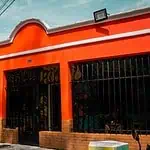 Farbenfrohe Gebäudefassade mit orangefarbener Farbe und urbaner Dekoration für Veranstaltungen und gesellschaftliche Zusammenkünfte in Bogotá. Ideal für die Bewerbung von Veranstaltungen und Marketing in kreativen Räumen.