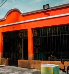 Farbenfrohe Gebäudefassade mit orangefarbener Farbe und urbaner Dekoration für Veranstaltungen und gesellschaftliche Zusammenkünfte in Bogotá. Ideal für die Bewerbung von Veranstaltungen und Marketing in kreativen Räumen.