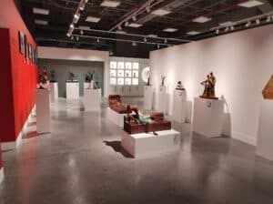 Arte y esculturas modernas en exhibición en una galería de arte en Colombia, con iluminación artística y disposición en pedestales blancos.