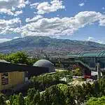 Moderno centro de eventos en Medellín con vistas a la ciudad y las montañas, con arquitectura moderna y rodeado de verdes espacios al aire libre, en un entorno natural y urbano.