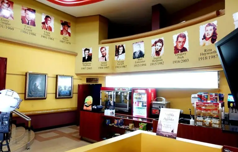 Signatures numérisées des visages de personnages historiques lors d'une exposition dans un lieu public, avec un distributeur automatique et une affiche promotionnelle au premier plan.