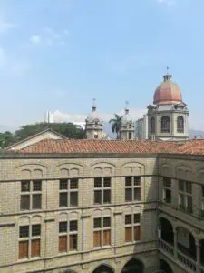 Rotes Ziegeldach, Kuppeltürme und eine Uhr auf einem Gebäude klassischer Architektur in einer Stadtlandschaft mit klarem Himmel in Bogotá, Kolumbien.