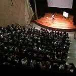 Presentation in an auditorium with a conference, attentive audience, stage with projector, easy access, corporate event, motivational talk, training, business training, technology, and networking.