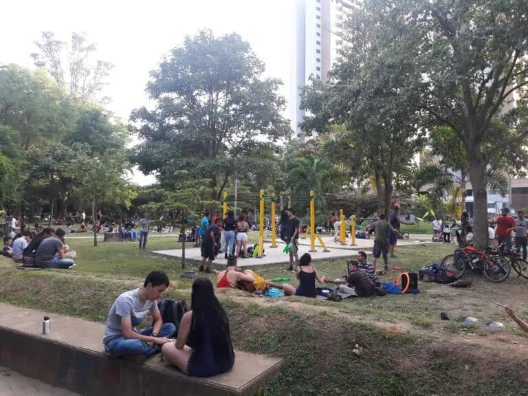 Des jeunes dans un parc public profitant d'activités de plein air, entourés de nature et d'installations sportives dans un cadre urbain en Colombie.
