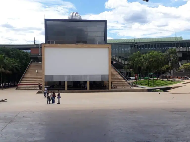 Auf einer riesigen Leinwand in einem öffentlichen Veranstaltungsraum in Bogotá wird ein moderner Veranstaltungsort mit Außenbereichen, monumentalen Treppen und Gärten in einem urbanen Umfeld gezeigt.