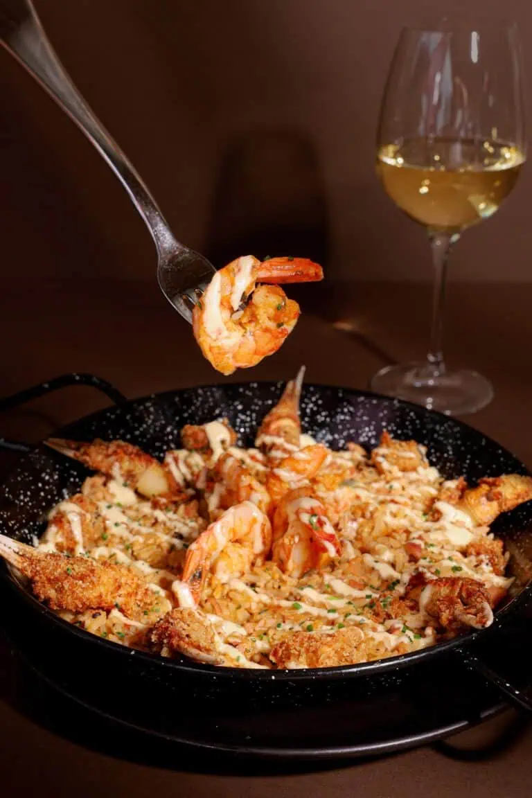 Köstliche Meeresfrüchte-Paella mit Garnelen und Tintenfisch, begleitet von einem Glas Weißwein in elegantem Ambiente. Perfekt für Veranstaltungen und Feiern in Kolumbien.