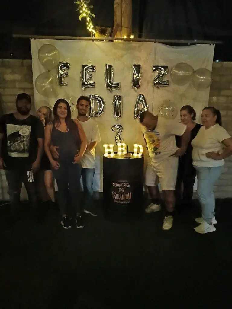 Fête d'anniversaire avec un groupe d'amis célébrant à l'intérieur avec des décorations dorées et des ballons, lors d'un événement d'entreprise Eventario.