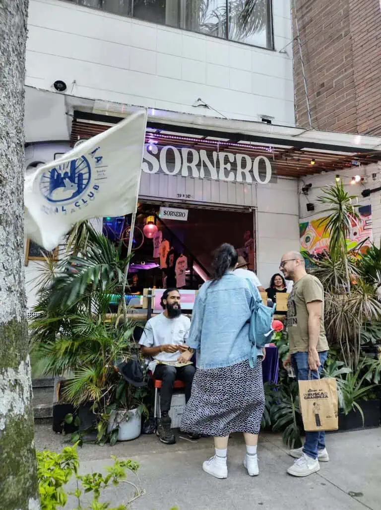 SORNERO 酒吧入口处悬挂着社交俱乐部的全新旗帜，人们在绿植环绕、现代装饰的公共街道上聊天，享受着这里的氛围。