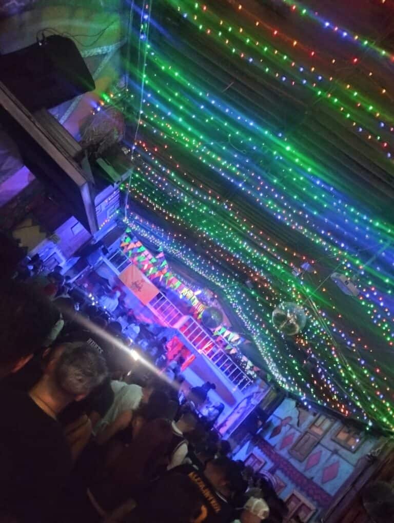 Colores de luces navideñas en espectáculo en interior con decoraciones vibrantes, ambiente festivo y público disfrutando del evento.