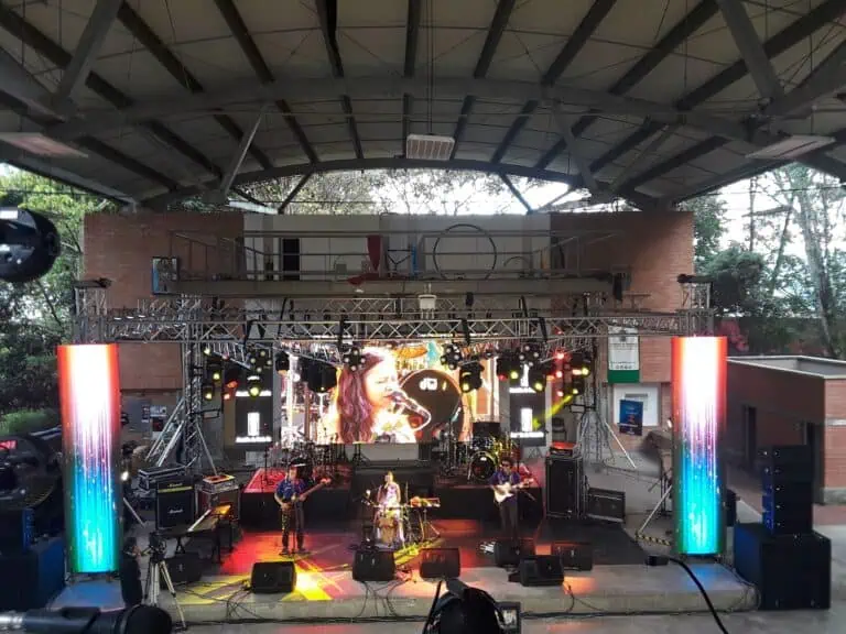 Open-Stage-Konzert mit einer Musikgruppe bei einer professionell organisierten Veranstaltung mit Beleuchtung und großer Leinwand auf einem Open-Air-Gelände in Kolumbien.