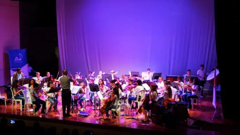 Orchestre d'enfants en concert dans un théâtre doucement éclairé.