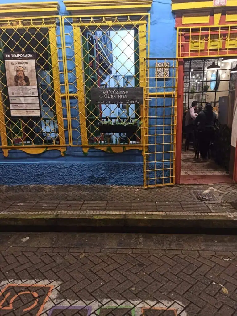 Alt text: 位于波哥大步行街的餐厅外立面，黄色大门、活动标志和可见的内部氛围，突显了当地的文化和美食。
