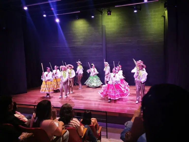 在哥伦比亚，一群哥伦比亚传统舞蹈演员在剧院舞台上表演，观众正在观看一场文化活动。