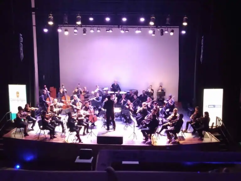 一支乐队在紫色灯光照亮的舞台上，在文化活动中，用古典乐器进行现场演奏。