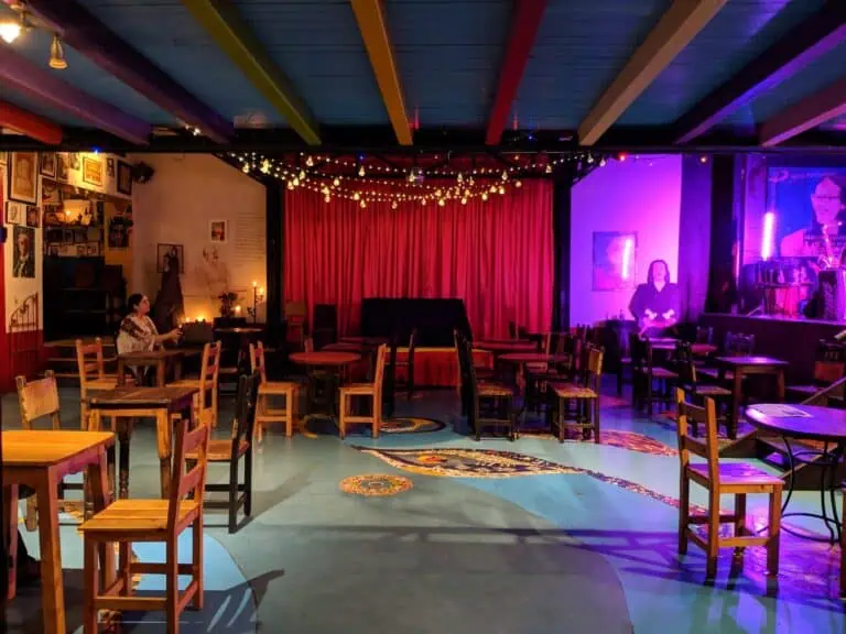 Eventario-Live-Konzert-Unterhaltung-Spaß-Events-für-Erwachsene-Musikkunst-intime-und-gemütliche-Atmosphäre, Anwesenheit von Künstlern auf der Bühne, Atmosphäre mit warmem Licht und künstlerischer Dekoration, Musikveranstaltungsszene in einem Raum mit gemütlicher Atmosphäre und künstlerischer Einrichtung, Konzertbühne in einem Innenraum mit entspannter Atmosphäre und Bohème-Dekor.