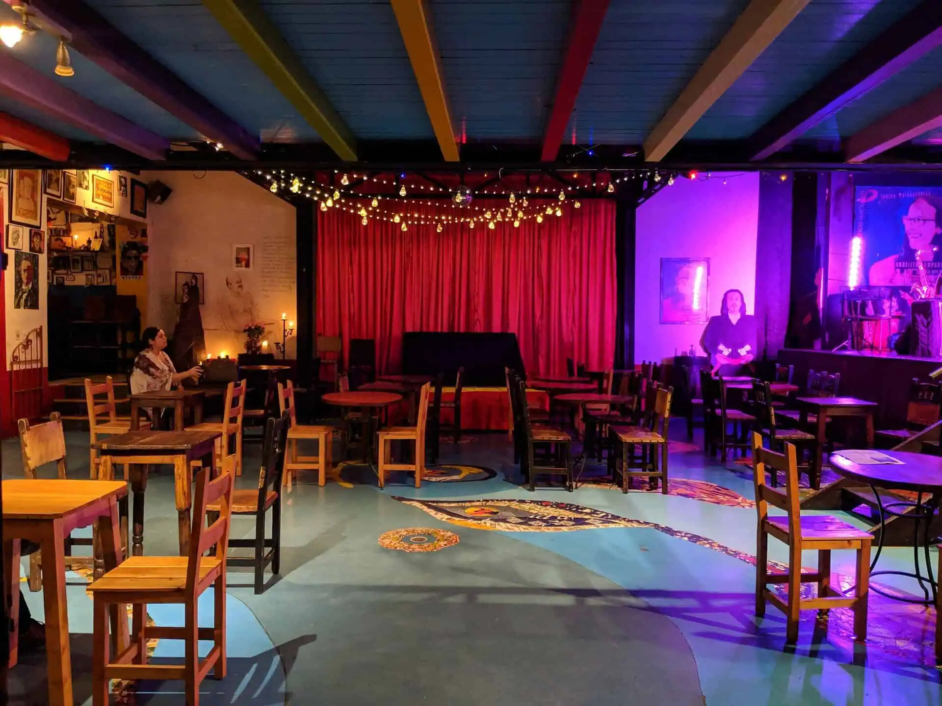 Eventario-Live-Konzert-Unterhaltung-Spaß-Events-für-Erwachsene-Musikkunst-intime-und-gemütliche-Atmosphäre, Anwesenheit von Künstlern auf der Bühne, Atmosphäre mit warmem Licht und künstlerischer Dekoration, Musikveranstaltungsszene in einem Raum mit gemütlicher Atmosphäre und künstlerischer Einrichtung, Konzertbühne in einem Innenraum mit entspannter Atmosphäre und Bohème-Dekor.