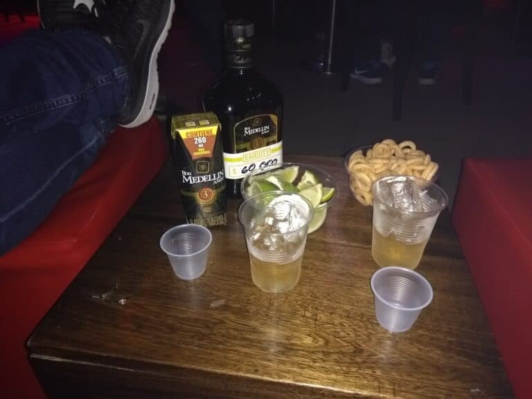 Ron Medellín 3 años, celebración con tequila, limones, torciditos y cervezas en una mesa de bar. Momentos de diversión y amigos compartiendo bebidas en un ambiente festivo.
