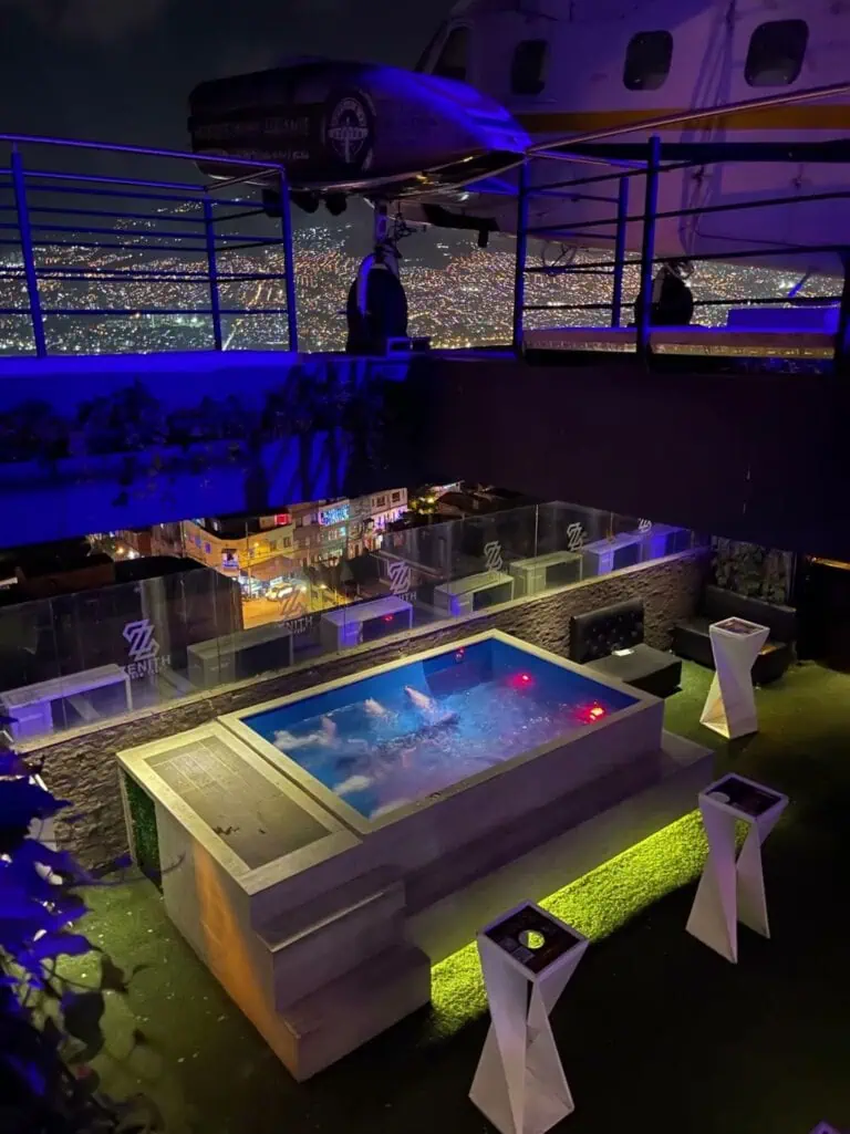 Jacuzzi de canto em cobertura com vista noturna para a cidade iluminada de Medellín, ideal para eventos exclusivos e experiências de hospedagem premium.