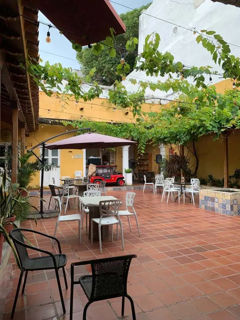 Profitez d'un espace extérieur à l'ambiance décontractée et chaleureuse, avec tables, chaises et ombre sur une terrasse agrémentée de plantes, de luminaires et d'éléments vintage. Idéal pour les événements et les moments conviviaux dans un cadre naturel.