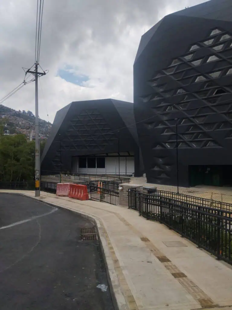 Un bâtiment moderne à l'architecture avant-gardiste avec une façade noire et une structure géométrique, dans un cadre urbain avec un ciel nuageux, idéal pour les événements et les conférences.