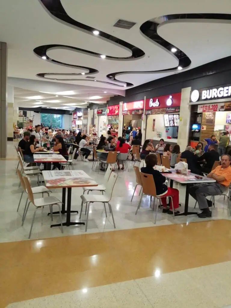 购物中心内出售食品和饮料，顾客们在餐桌旁享用美食。