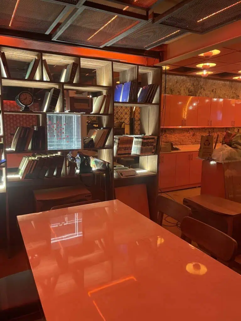 Bibliothèque événementielle intérieure avec étagères en bois, livres et objets décoratifs dans un environnement d'éclairage chaleureux et moderne, idéale pour les événements et réunions d'entreprise en Colombie.