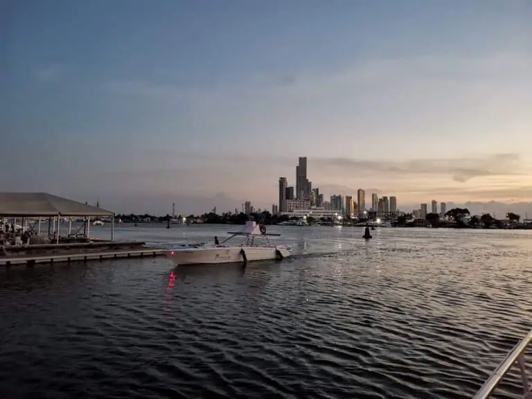 夕阳西下，哥伦比亚麦德林市海湾中的船只，背景是摩天大楼；麦德林的城市和海洋景观、夜景、旅游、活动和夜生活。