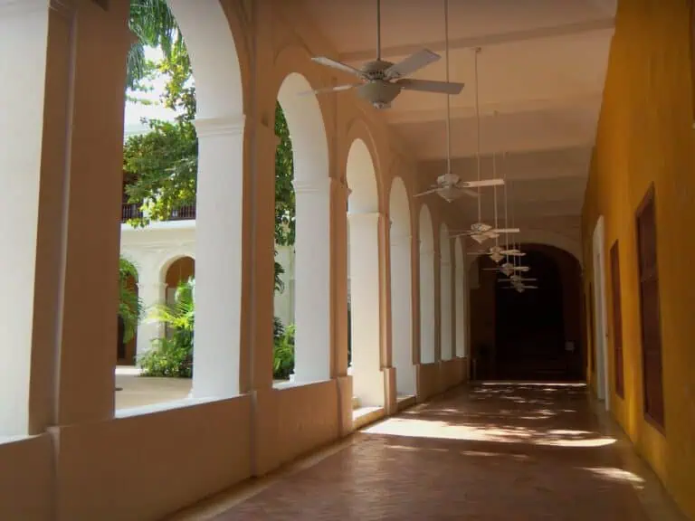 Sols et plafonds modernes dans une cour coloniale avec ventilateurs et arches en verre, un cadre idéal pour des événements et des réunions dans des espaces historiques et élégants.