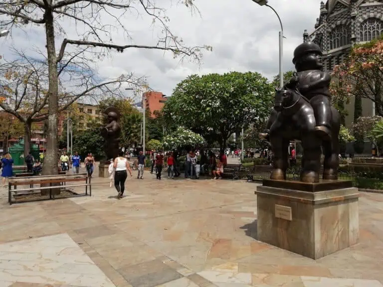 在哥伦比亚波哥大的一个公园里，现代雕塑林立，游客们在多云的天气里享受着公园的空间和自然风光。