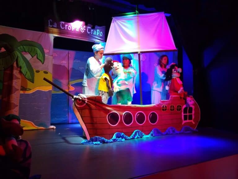 Barco de teatro con marionetas y personajes en una obra infantil, escenario colorido y efectos de iluminación para eventos y espectáculos en vivo.