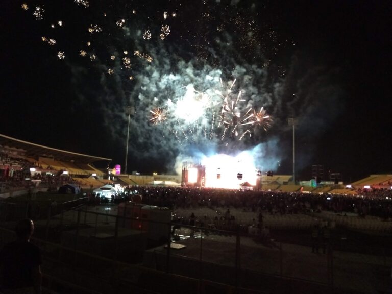 Espectáculo de fuegos artificiales en estadio durante evento nocturno en Colombia. Celebración con luces y pirotecnia en un concierto o evento deportivo al aire libre.