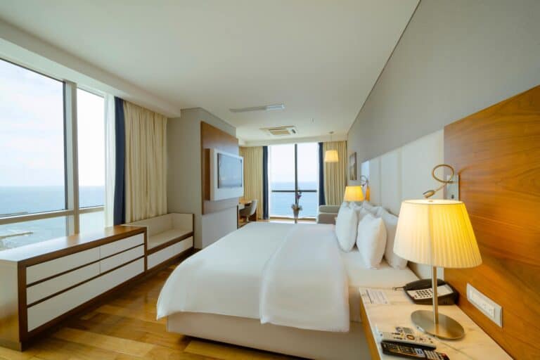 Esquinas modernas y elegantes en una habitación de hotel con vista al mar, camas cómodas, iluminación cálida y detalles de diseño que generan un ambiente acogedor y relajante.
