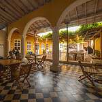Moderno espacio interior de restaurante o café con arcadas, columnas y área al aire libre decorada con luces y vegetación, ideal para eventos y reuniones sociales.