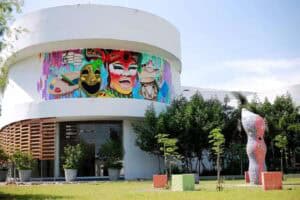 Colorido mural artístico en edificio moderno, foco en cultura y eventos con decoración vibrante y esculturas en un espacio al aire libre en Colombia.