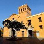 Catedral colonial en el centro histórico de Cartagena, con fachada amarilla, torre y árbol en primer plano, ideal para eventos culturales y turísticos en Colombia.