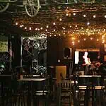 酒吧氛围温馨舒适，有吊灯照明，墙上装饰着艺术品和自行车，是举办文化活动和情侣或家庭娱乐之夜的理想场所。