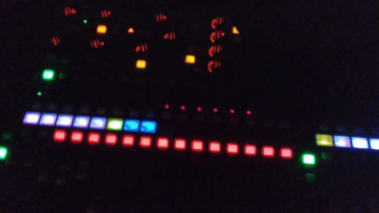 Controles de consola de DJ con luces LED en un ambiente oscuro, ideales para eventos y fiestas. Diseño moderno y tecnología avanzada para profesionales del entretenimiento y la música en vivo.