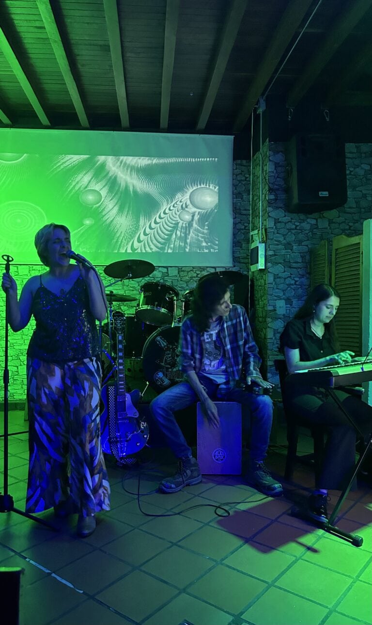 Banda musical en evento en interior con iluminación verde, escenario con instrumentos y proyección digital, ideal para eventos empresariales y sociales con entretenimiento en vivo.