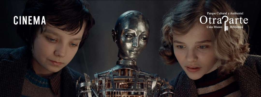 Crianzas observando una marioneta de robot metálico en un espacio cultural, promoviendo el cine infantil y actividades educativas en Parque Cultural y Ambiental OtraParte en Colombia.